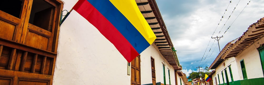 Colombian flag waves outside of a home on an empty street.